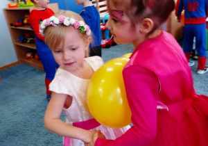 Dwie dziewczynki tańczą trzymając żółty balon